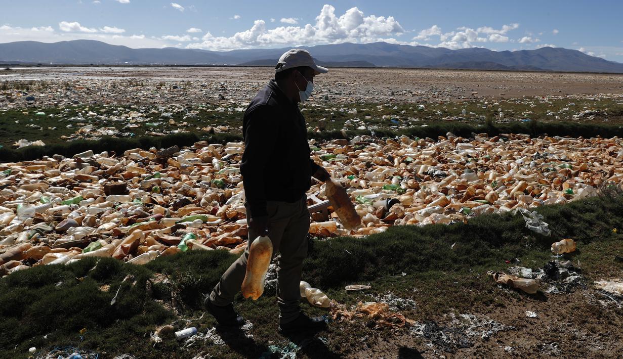 Limbert Sanchez, anggota Pusat Ekologi dan Masyarakat Andes, membawa botol yang diambil dari lautan sampah yang memenuhi Sungai Tagaret, Bolivia, yang kering, Kamis (25/3/2021). Sungai ini mengalir ke Danau Uru Uru dengan membawa sampah-sampah yang mencemari danau. (AP Photo / Juan Karita)