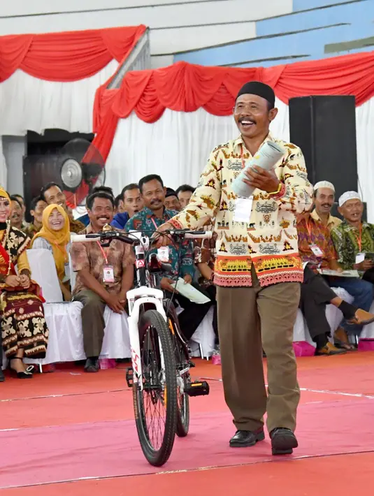 Warga tertawa karena mendapatkan hadiah sepeda dari Presiden Jokowi dalam acara pembagian sertifikat di GOR Way Handak, Kalianda, Lampung Selatan, Lampung, Minggu (21/1). (Liputan6.com/Pool/Laily Rachev-Biro Pers Setpres)