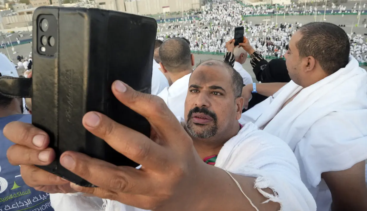 Seorang jemaah haji melakukan panggilan video ke kerabatnya dari Jabal Rahmah di Padang Arafah, dekat Kota Suci Mekkah, Arab Saudi, 8 Juli 2022. (AP Photo/Amr Nabil)
