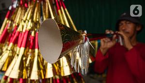 Pedagang sedang menjajal terompet buatannya di kawasan Glodok, Jakarta, Selasa (26/12/2023). (Liputan6.com/Faizal Fanani)