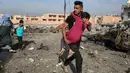 Tentara pasukan khusus Irak berjalan sambil menggendong seorang gadis yang terluka menyusul serangan bom mobil bunuh diri yang dilakukan militan ISIS di kota Tahrir, Irak, 17 November 2016. (REUTERS/Goran Tomasevic)