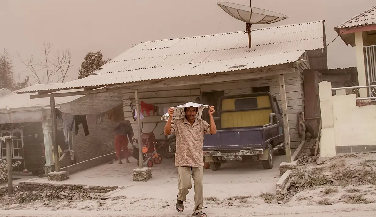 Warga menutupi kepalanya untuk menghindari abu vulkanik akibat erupsi Gunung Sinabung yang menghujani Desa Tiga Pancur, Karo, Sumatera Utara, Rabu (2/8). Sinabung meluncurkan awan panas hingga 20 kali sepanjang hari ini disertai erupsi. (IVAN DAMANIK/AFP)