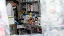 Pegawai terlihat dari balik lapisan plastik untuk mengurangi kontak fisik di sebuah apotek di Baghdad, Irak, Selasa (14/4/2020). Kementerian Kesehatan Irak pada Selasa (14/4/2020) mengatakan total 1.400 kasus virus corona COVID-19 terkonfirmasi di negara tersebut. (Xinhua)