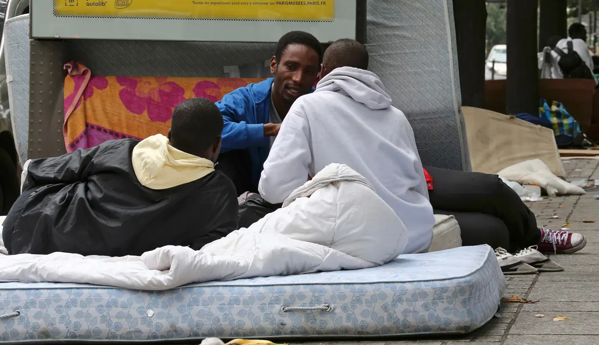 Sejumlah imigran berbincang di atas kasur di sebuah kamp darurat di jalanan Kota Paris, Prancis, Selasa (6/9). Para imigran berkulit hitam tersebut hidup terlantar di pinggir jalan kota tersebut. (REUTERS/Benoit Tessier)