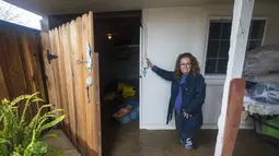 Teresa Fuentes melihat barang-barangnya rusak akibat banjir di rumahnya di College Road di Watsonville, California, Jumat, 10 Maret 2023. Evakuasi diperintahkan di dekat Watsonville di mana air sungai meluap dan memenuhi jalan raya dengan air setinggi beberapa kaki, mengancam puluhan rumah dengan banjir. (AP Photo/Nic Coury)