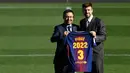 Bek Spanyol, Gerard Pique dan Presiden Barcelona FC, Josep Maria  berpose memegang jersey Barcelona pada pengumuman perpanjangan kontraknya di stadion Camp Nou, Senin (29/1). Pique memperpanjang kontraknya bersama Barcelona hingga 2022. (LLUIS GENE/AFP)