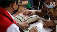 Umat muslim membayar zakat fitrah kepada amil zakat di Masjid Istiqlal, Jakarta, Jumat (7/5/2021). Panitia Zakat Masjid Istiqlal mulai membuka layanan pembayaran zakat fitrah dengan pembayaran senilai Rp 50 ribu atau 3,5 liter beras. (Liputan6.com/Faizal Fanani)