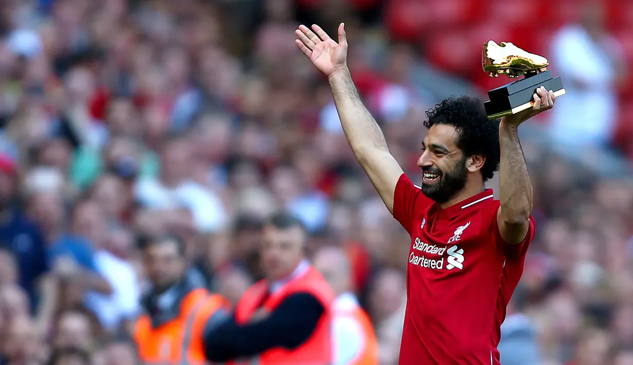 Mohamed Salah mengangkat penghargaan Sepatu Emas yang diraihnya setelah Liverpool menekuk Brighton and Hove Albion di Anfield, Minggu (13/5). Salah menyumbangkan 32 gol, unggul dua gol dari bomber Tottenham Hotspur, Harry Kane. (Dave Thompson/PA via AP)