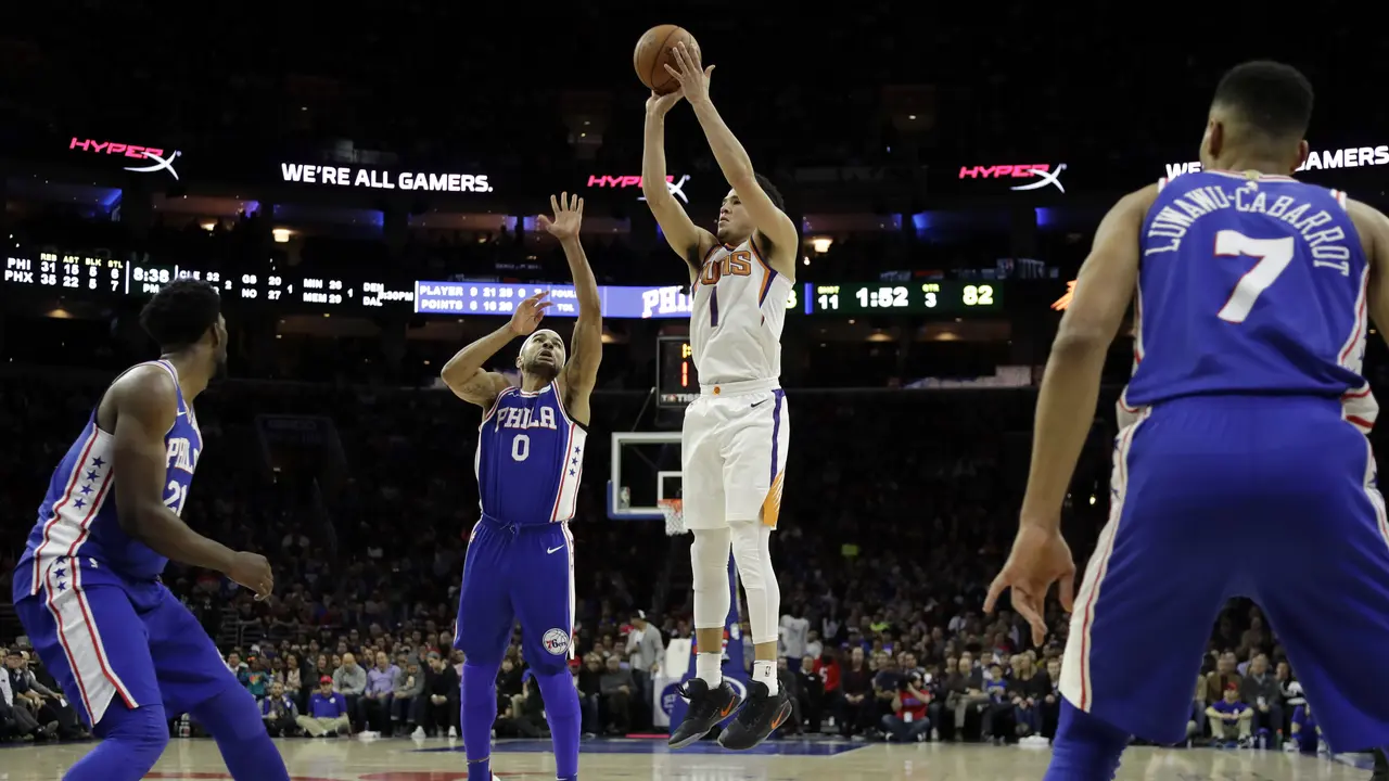 Devin Booker memasukkan bola saat Suns melawan Sixers