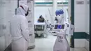 Perawat berdiri di dekat prototipe robot CIRA-03 untuk mengumpulkan sampel pengujian Swab Test COVID-19 di koridor rumah sakit swasta di kota Tanta, Mesir pada 20 Maret 2021. Prototipe robot itu bagian dari proyek mandiri untuk membantu dokter dalam meredam pandemi COVID-19. (Khaled DESOUKI/AFP)