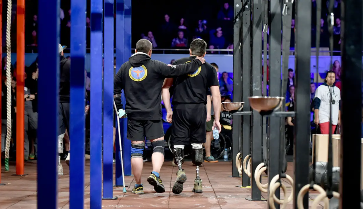 Kedua peserta berjalan bersama saat mengikuti kompetisi final CrossFit "Game of Heroes" di Kiev, Ukraina (24/12). (AFP/Sergei Supinsky)