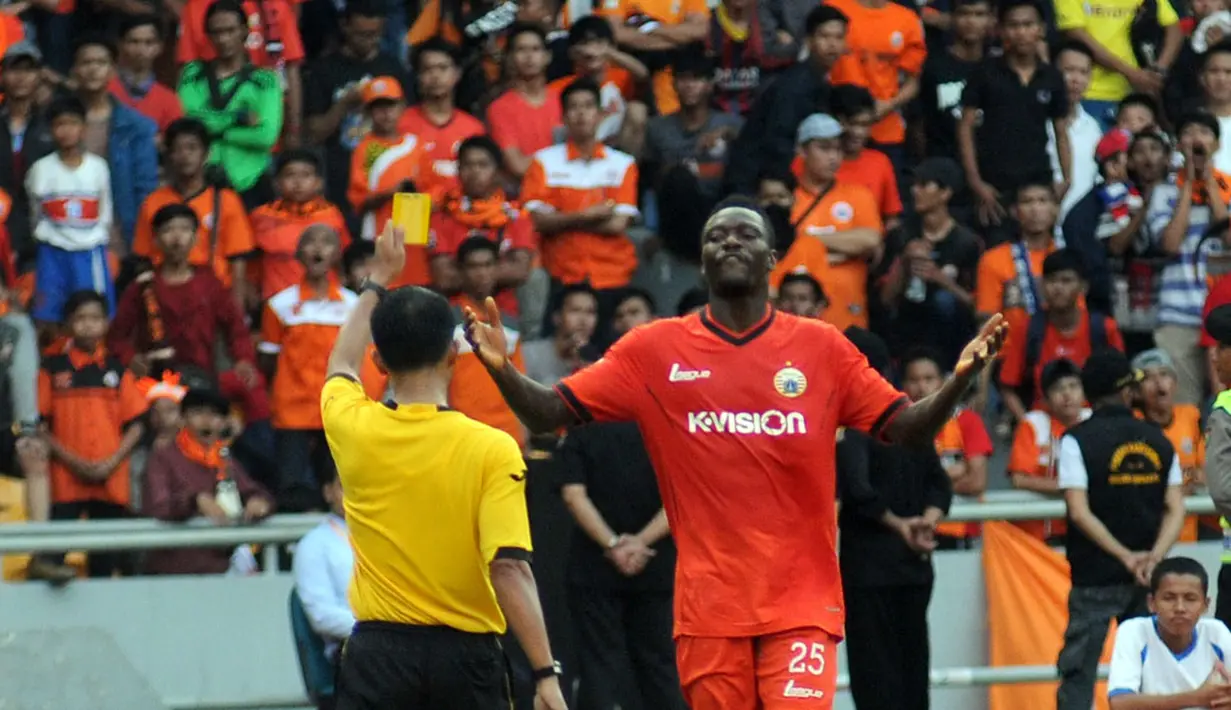 Pemain depan Persija Jakarta, Edi Foday Boakay (kanan), mendapat kartu kuning dari wasit Handri Kristanto saat berlaga di Stadion GBK, (10/8/2014). (Liputan6.com/Helmi Fithriansyah)  