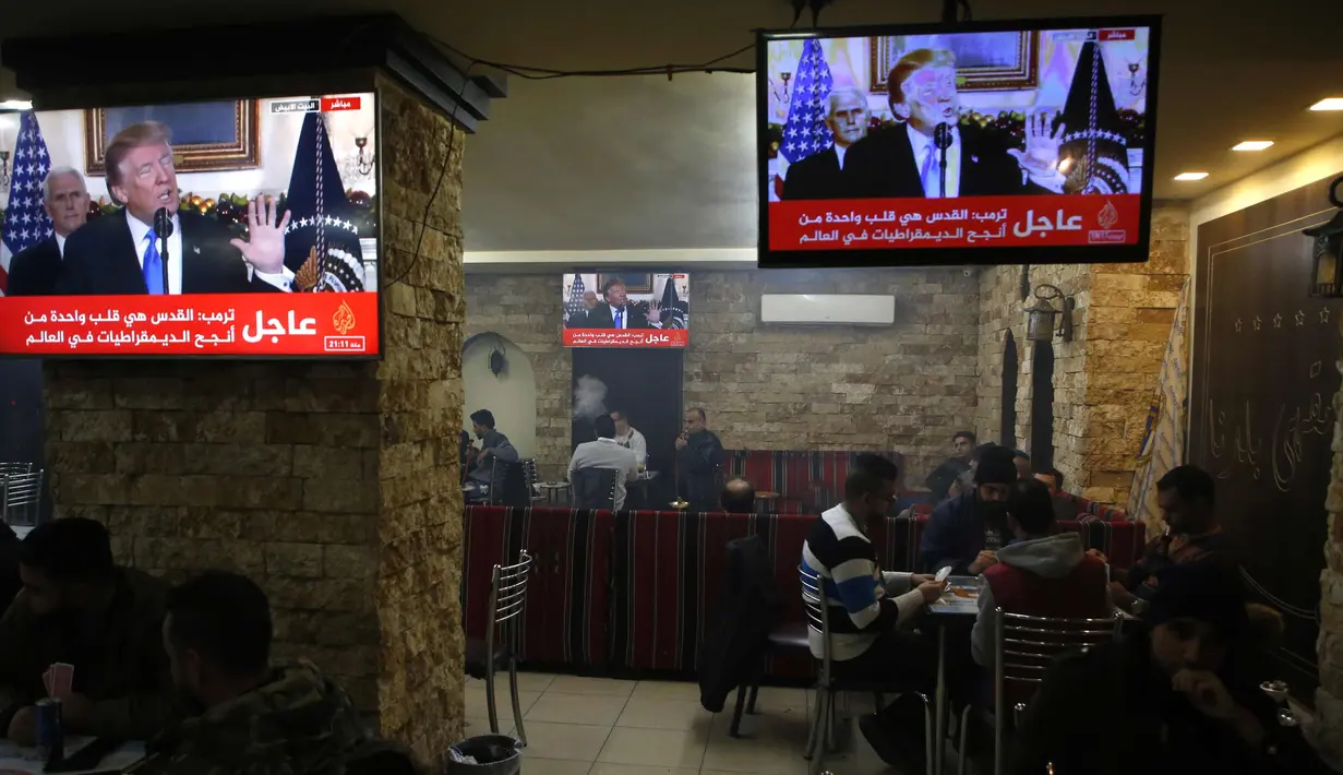 Warga Palestina berada di kafe di kota Ramallah di Tepi Barat saat sebuah siaran televisi menayangkan pidato Presiden AS, Donald Trump mengumumkan AS mengakui Yerusalem sebagai ibu kota Israel (6/12). (AFP Photo/Abbas Momani)