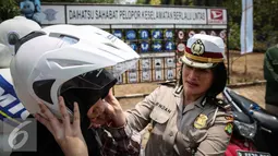 Petugas membantu pelajar cara mengenakan helm yang benar pada sesi edukasi dan sosialisasi program Road Safety "Tunjukkin Safetymu! Ayo Uji SIM", di Jakarta, Sabtu (19/9/2015). (Liputan6.com/Faizal Fanani)