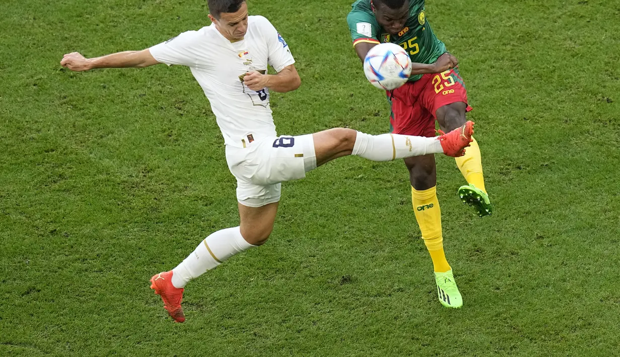 Bek Kamerun Tolo Nouhou berebut bola dengan gelandang Serbia Nemanja Maksimovic pada matchday 2 Grup G Piala Dunia 2022 di Al Janoub Stadium, Senin (28/11/2022). Kamerun bisa mengejar ketertinggalannya dari Serbia. (AP Photo//Pavel Golovkin)