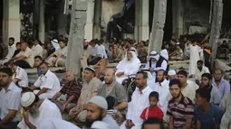 Warga muslim Palestina mendengarkan khotbah saat melaksanakan salat Idul Fitri di salah satu masjid yang rusak parah akibat serangan militer Israel di Rafah, Jalur Gaza, Senin (28/7/14).(REUTERS/Ibraheem Abu Mustafa)