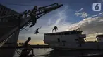 Anak-anak melompat dari atas kapal yang tengah bersandar di Pelabuhan Sunda Kelapa, Jakarta, Senin (6/7/2020). Lompatan dari atas kapal tanpa pengaman ini dilakukan sore hari menjelang matahari terbenam. (Liputan6.com/Fery Pradolo)