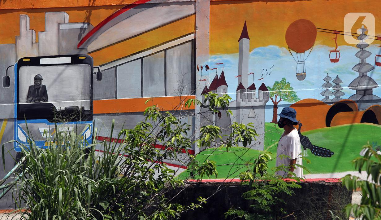 Pekerja berjalan di depan mural Kota Jakarta, Tanah Kusir, Kebayoran Lama, Jakarta, Jumat (26/11/2021). Mural tersebut bertemakan Kota Jakarta dengan gambar ikon seperti ondel-ondel, Monas hingga transportasi. (Liputan6.com/Herman Zakharia)
