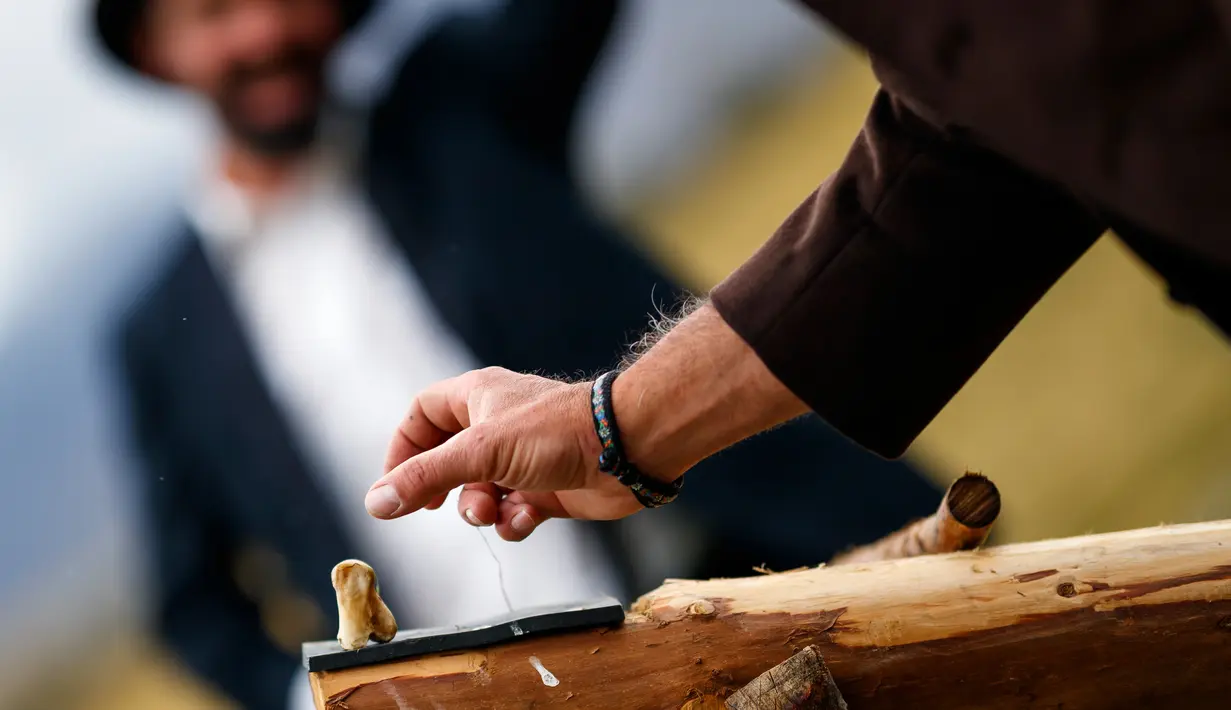 Seorang pria bersiap memukul tulang kaki sapi dengan tongkat selama pertandingan 'Gilihuesine' di resor alpine Bettmeralp, Swiss (16/9). Gilihuesine merupakan permainan campuran golf modern dan bisbol. (Valentin Flauraud/Keystone via AP)