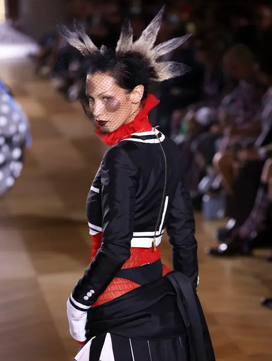 <p>Bella Hadid mempersembahkan kreasi Thom Browne saat peragaan busana Musim Semi-Musim Panas 2023 sebagai bagian dari Paris Womenswear Fashion Week, Paris, Prancis, 3 Oktober 2022. Dia mengenakan rok mini hitam berlipat rendah yang bertumpuk pada pinggulnya dan memamerkan pakaian dalam hitamnya di dalamnya. (Photo by Vianney Le Caer/Invision/AP)</p>