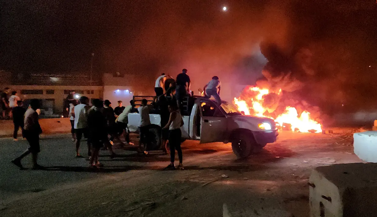 Warga Libya membakar ban saat mereka melakukan protes setelah Menteri Luar Negeri Najla Mangoush bertemu secara informal dengan Menlu Israel, di Tripoli, Senin (28/8/2023). (Photo by Mahmud TURKIA / AFP)