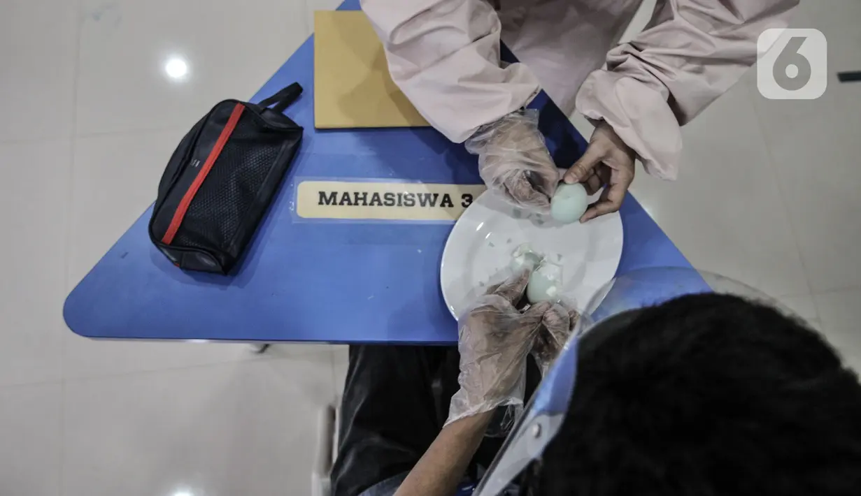 Terapis atau pengajar membimbing mahasiswa berkebutuhan khusus mengupas telur asin di Lembaga Pendidikan dan Keterampilan Kampusnya Manusia, Kranggan, Bekasi, Jawa Barat, Kamis (3/12/2020). Terapi ini juga mengembangkan kemampuan berwirausaha. (merdeka.com/Iqbal S. Nugroho)