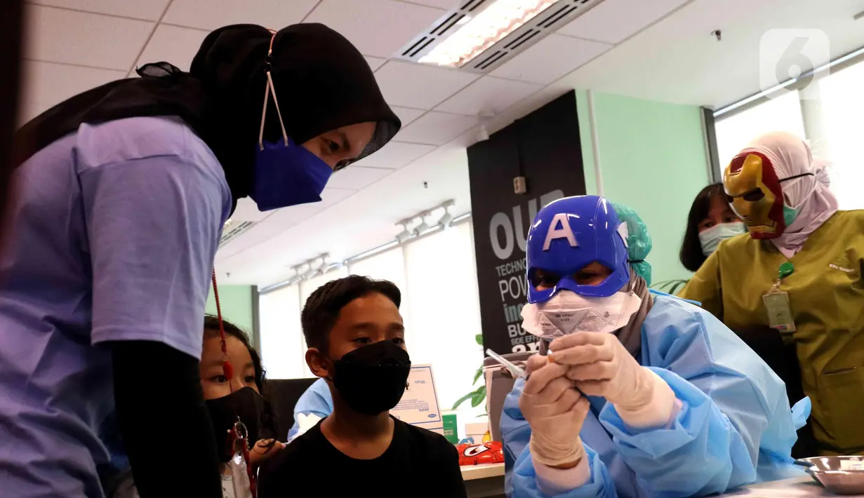 Petugas medis dengan mengenakan topeng superhero bersiap menyuntikkan vaksin Sinonvac kepada anak-anak saat mengikuti vaksinasi kedua di Gedung  Otoritas Jasa Keuangan (OJK), Jakarta, Minggu (16/01/2022). (Liputan6.com/Angga Yuniar)
