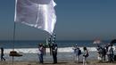 Warga setempat melakukan prosesi keagamaan dekat seni instalasi kontemporer "Tu huella es el camino, tu bandera es de paz" di Playas de Tijuana, Meksiko (7/10). (AFP Photo/Guillermo Arias)