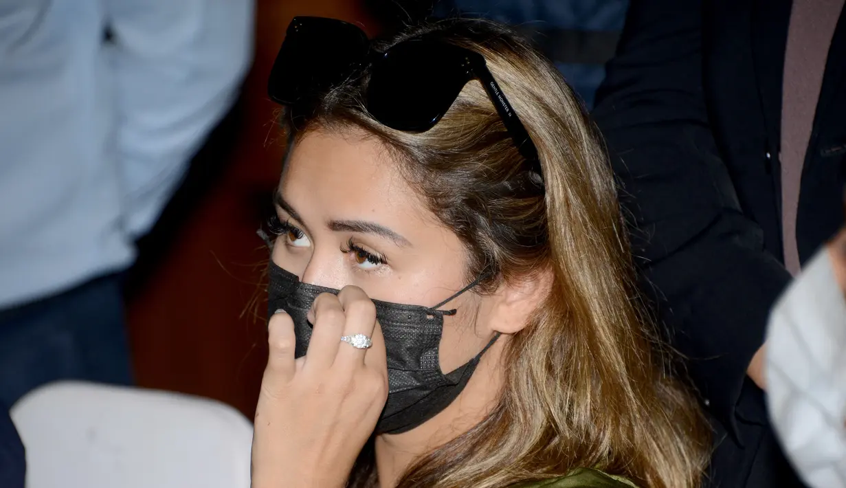 Leia Se, perempuan asal Rusia merapikan masker saat menghadiri konferensi pers sebelum dideportasi di kantor Kemenkumham Bali, Rabu (5/5/2021). Leia Se diamankan pihak imigrasi karena membuat konten prank melukis wajah mirip masker di Bali akhirnya dideportasi. (AFP/Sonny Tumbelaka)
