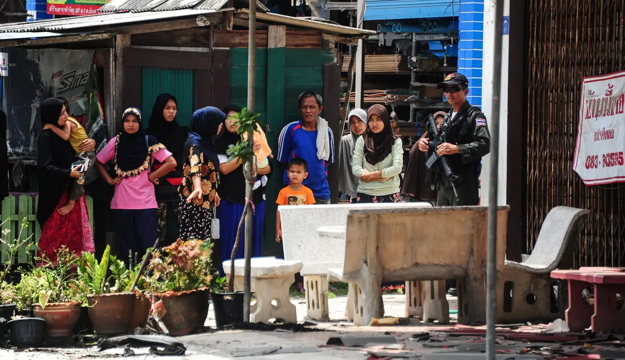 Warga berkumpul di lokasi ledakan bom motor di luar sebuah sekolah di distrik Tak Bai, Thailand, Selasa (6/9). Bom yang disembunyikan di tangki bahan bakar sepeda motor meledak saat para siswa dan guru memasuki halaman sekolah. (Madaree TOHLALA/AFP)