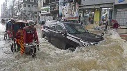 Para penumpang melewati jalan yang dilalui air setelah hujan lebat di Dhaka (21/7/2020). Korban tewas akibat hujan lebat di Asia Selatan telah meningkat menjadi hampir 200, ketika Bangladesh dan Nepal memperingatkan bahwa naiknya air akan membawa banjir lebih lanjut. (AFP/Munir Uz zaman)