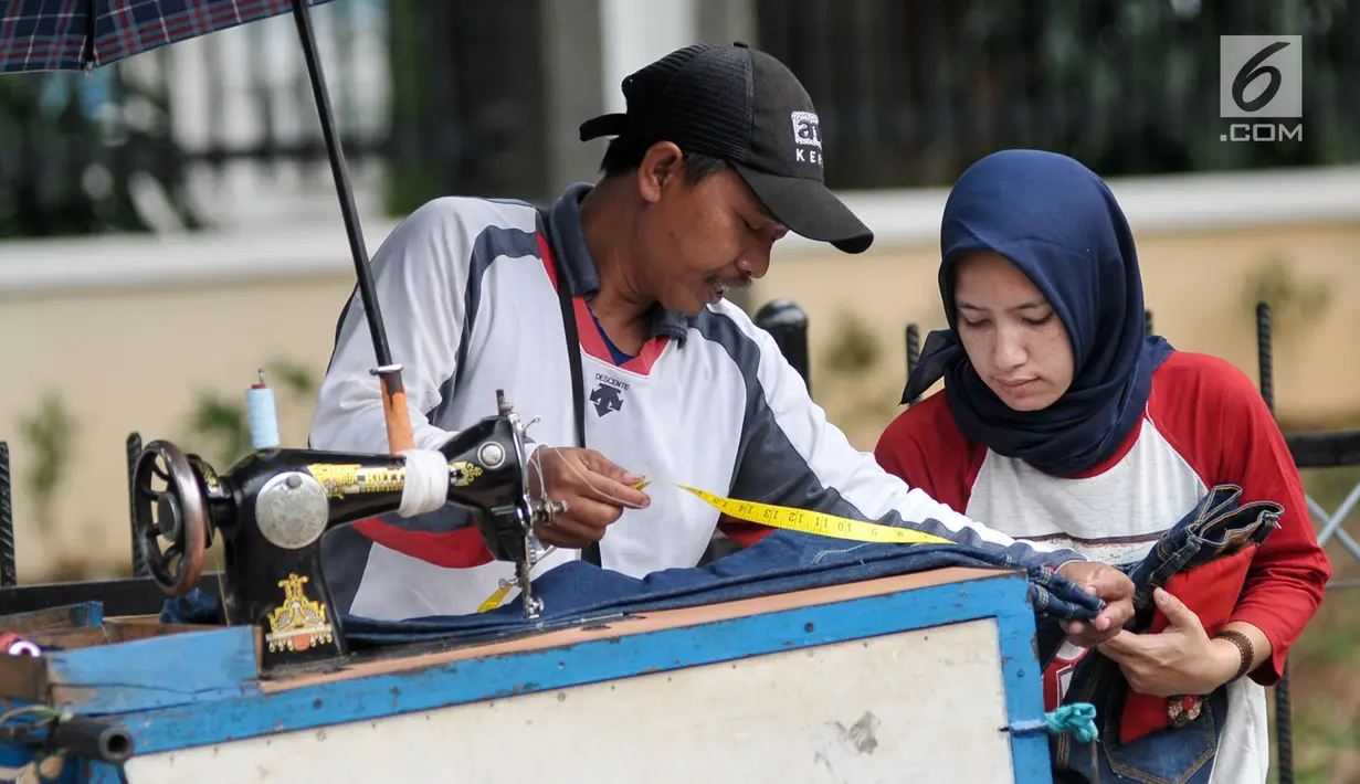Penjahit keliling mengukur pakaian pelanggan yang akan dijahit ulang, Jakarta, Kamis (22/6). Jelang lebaran, penjahit keliling mulai banyak menerima orderan warga untuk sekedar memotong atau mengecilkan pakaian. (Liputan6.com/Yoppy Renato)