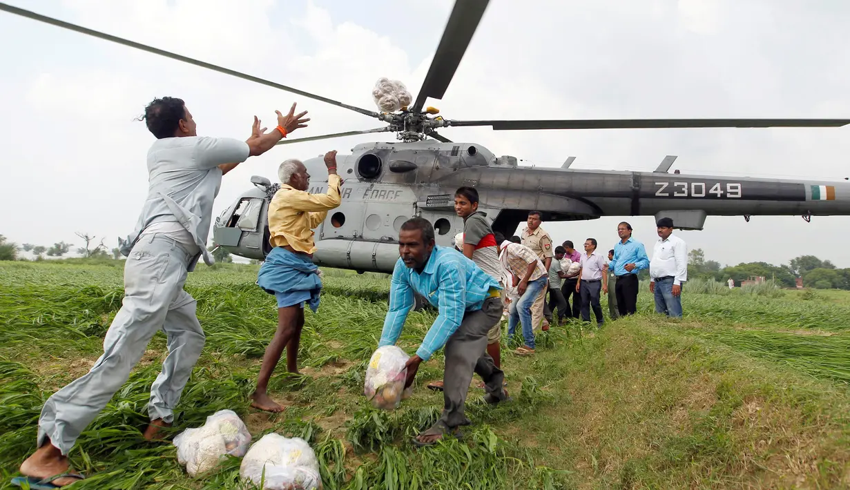 Warga korban banjir mendistribusikan bantuan paket makanan dari helikopter Angkatan Udara India di pinggiran Allahabad, India, Kamis. (25/08). Korban tewas akibat banjir menjelang akhir Agustus ini telah mencapai 300 orang (REUTERS / Jitendra Prakash)