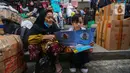 Anak-anak yang hendak ikut dalam perjalanan mudik membaca buku yang diberikan secara cuma-cuma oleh Badan Bahasa Kementerian Pendidikan, Kebudayaan, Riset, dan Teknologi (Kemendikbudristek) di Teriminal Kalideres, Jakarta, Selasa (2/4/2024). (Liputan6.com/Angga Yuniar)