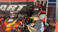 Ivan (duduk baju hitam) sedang setting motor tim ART Fams menggunakan laptop pada seri pertama Yamaha Cup Race 2025 di Sirkuit Sport Centre Rumbai, Pekanbaru, Riau hari Minggu (18/05/2025). (Hendry Wibowo/Bola.com)