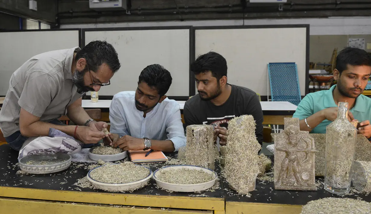 Desainer National Institute of Design (NID), Pravinsinh Solanki membimbing muridnya saat membuat karya seni dari uang kertas pecahan 500 dan 1.000 Rupee di Ahmedabad, India (26/4). (AFP PHOTO/SAM PANTHAKY)