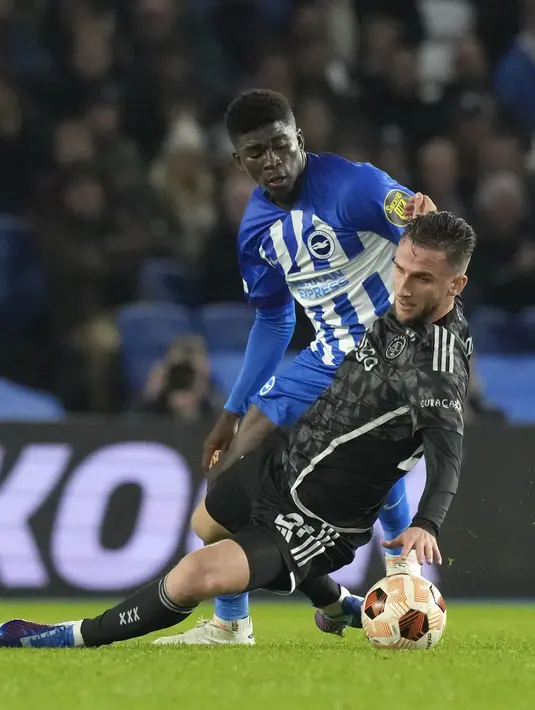 Pemain Brighton, Carlos Baleba (kiri) berusaha melewati penjagaan pemain Ajax Amsterdam, Branco van den Boomen pada laga Grup B Liga Europa 2023/2024 di American Express Community Stadium, Brighton, Inggris, Jumat (27/10/2023) dini hari WIB. (AP Photo/Frank Augstein)