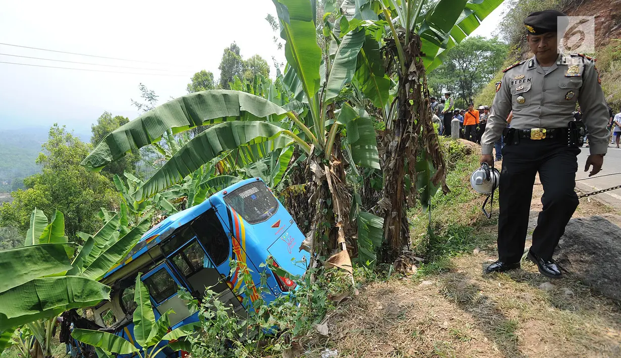 Petugas kepolisian berjalan dekat bus maut Jakarta Wisata Transport yang masuk jurang di jalur alternatif Cikidang, Sukabumi, Minggu (9/9). Bus pariwisata tersebut mengangkut 31 karyawan PT Catur Putra Raya Bogor dan dua awak. (Merdeka.com/Arie Basuki)