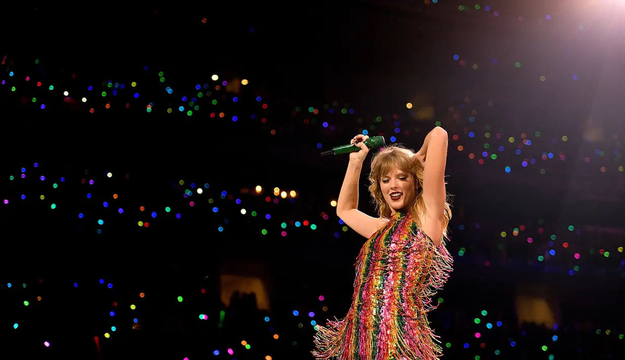 Di konser yang sama, Taylor Swift juga mengenakan bodysuit namun kali ini dengan garis warna-warni. Bodysuit bernuansa pink ini memiliki aksen fringes yang flowy.