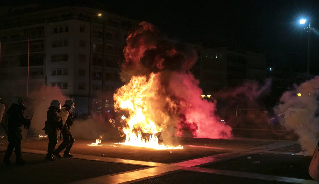 Polisi Yunani mengamankan area ketika pengunjuk rasa antivaksin melemparkan suar dan bom molotov selama rapat umum di alun-alun Syntagma, Athena tengah (24/7/2021). Lebih dari 4.000 orang berunjuk rasa di luar parlemen Yunani, Minggu (25/7/2021) waktu setempat. (AP Photo/Yorgos Karahalis)