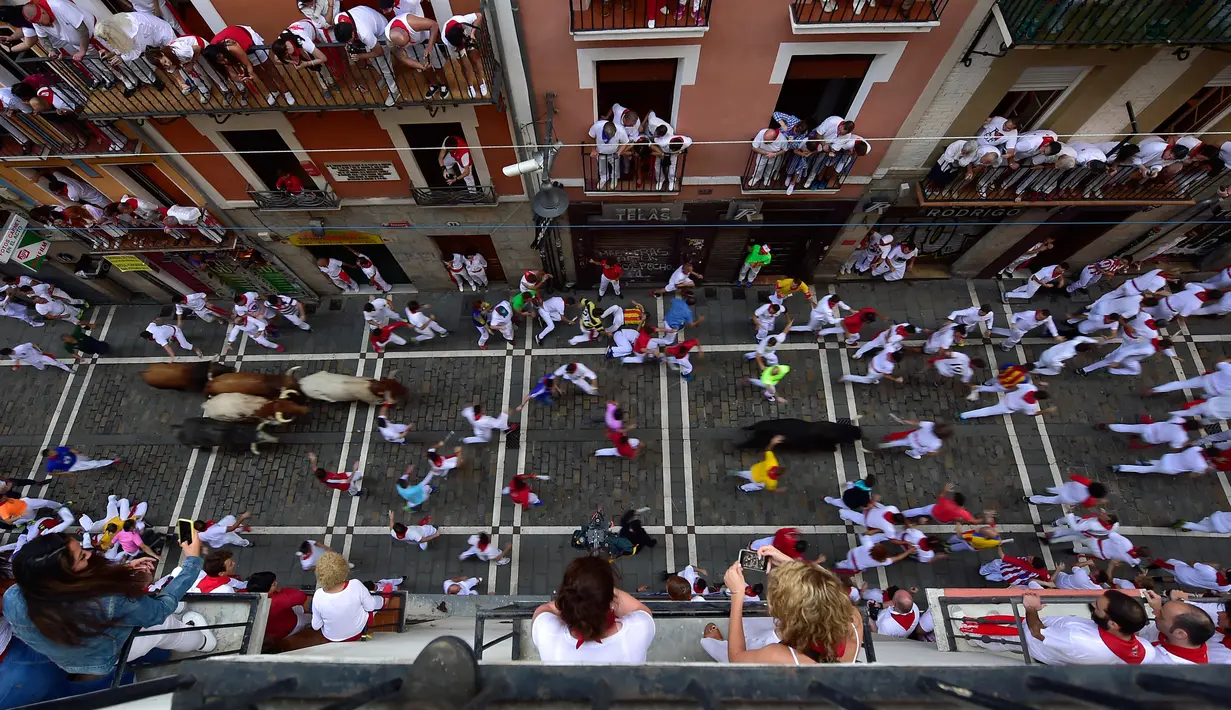 Orang-orang berlari menghindari serudukan banteng selama hari ketiga Festival San Fermin di Pamplona, Spanyol utara, (9/7). Ratusan orang dari seluruh dunia  setiap tahunnya ambil bagian dalam Festival Adu Banteng, San Fermin. (AP Photo/Alvaro Barrientos)