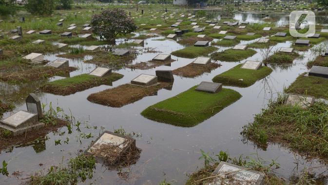 Banjir merendam sejumlah makam di Tempat Pemakaman Umum (TPU) Tanah Kusir, Jakarta, Jumat (3/1/2020). TPU Tanah Kusir terendam banjir setelah Kali Pesanggrahan meluap akibat intensitas hujan yang tinggi pada Rabu lalu. (merdeka.com/Imam Buhori)