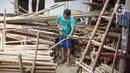 Perajin memotong bambu yang biasa digunakan sebagai tiang bendera di kawasan Manggarai, Jakarta, Kamis (6/8/2020). Bambu-bambu itu dijual dengan harga bervariasi, mulai dari Rp15ribu hingga Rp35ribu, tergantung ukurannya. (Liputan6.com/Immanuel Antonius)