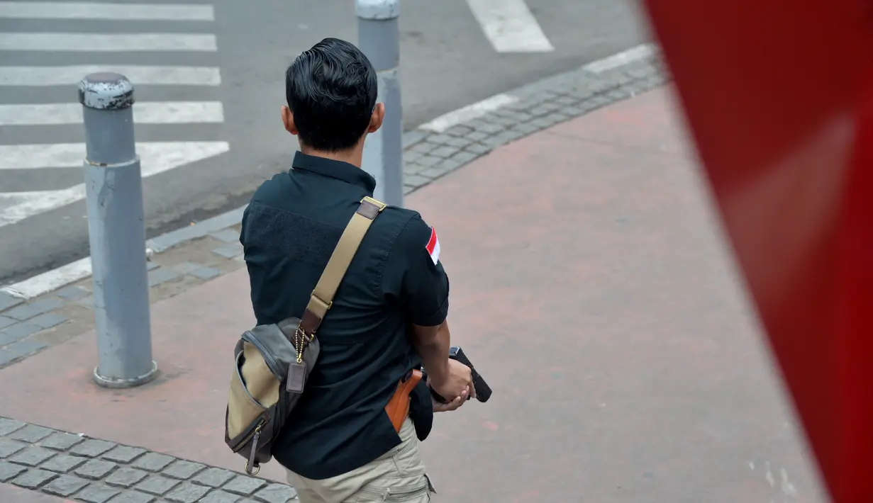 Seorang polisi berpakaian preman sambil memegang pistol tampak bersiaga mengejar pelaku ledakan di pospol Sarinah, Jakarta, Kamis (14/1). Baku tembak terjadi di depan Sarinah setelah suara ledakan ketiga terjadi.  (AFP PHOTO/Bay Ismoyo)
