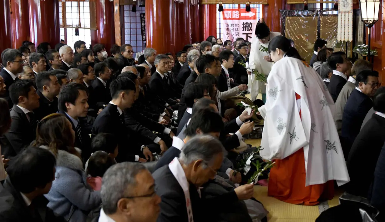 Seorang imam Shinto dan gadis Shinto memberikan "tamagushis" kepada pengusaha selama upacara awal tahun  di Kuil Kanda Myojin, Tokyo (4/1). (AFP Photo/Toshifumi Kitamura)