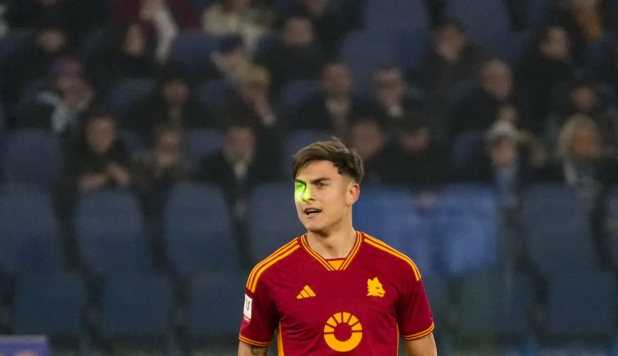 Sinar laser menyinari wajah penyerang AS Roma Paulo Dybala saat bersiap melakukan tendangan bebas pada laga perempat final Coppa Italia 2023/2024 melawan Lazio di Stadio Olimpico, Kamis (11/1/2024) dini hari WIB. (AP Photo/Gregorio Borgia)