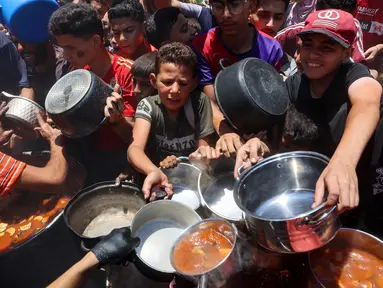 Warga Palestina berusaha mendapatkan makanan di dapur umum yang menyediakan makanan hangat di lingkungan Rimal, kota Gaza pada 18 Juni 2025. (Omar AL-QATTAA/AFP)