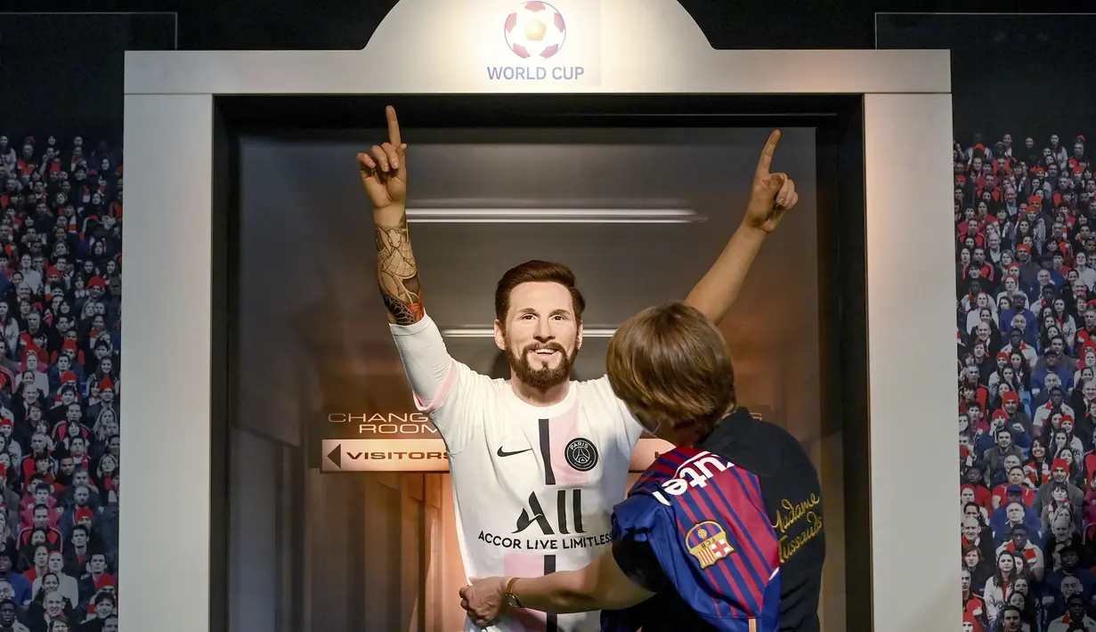 Seorang tim potret museum lilin Madame Tussauds Berlin, Karen Fries memakaikan jersey Paris Saint-Germain untuk patung lilin Lionel Messi di Madame Tussauds Berlin, Jerman, Rabu (11/7/2021). (AP Photo/Britta Pedersen/dpa via AP)