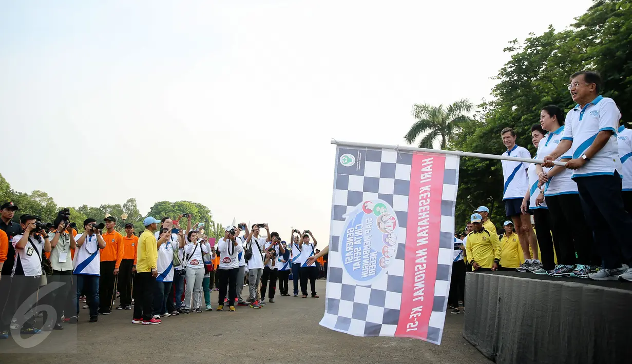 Wakil Presiden Jusuf Kalla memegang bendera tanda dimulainya jalan sehat  memperingati puncak Hari Kesehatan Nasional Ke-51 di Silang Monas, Jakarta, Minggu (6/12/2015). Acara tersebut dihadiri sebanyak 2000 peserta. (Liputan6.com/Faizal Fanani)