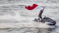 Atlet jetski Indonesia, Aqsa Aswar, mengibarkan bendera merah putih usai meraih medali emas pada nomor endurance runabout open cabang jetski Asian Games XVIII di Jetski Arena Ancol, Jakarta, Minggu (26/8/2018). (Bola.com/Vitalis Yogi Trisna)